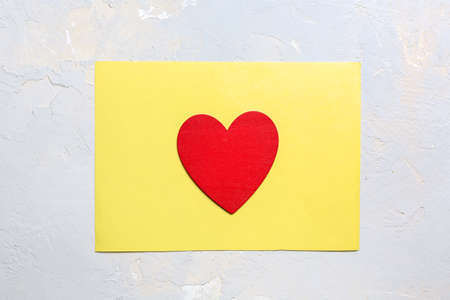 Red painted heart on yellow paper on gray textured background, Saint Valentine day minimalistic greeting card in ultimate gray and illuminate yellow colors of the 2021 yearの写真素材