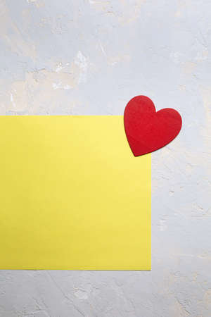 Red painted heart on yellow paper on gray textured background, Saint Valentine day minimalistic...