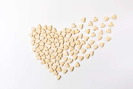 Heart-shaped little sweet cookies in form of dissolving heart on white background, minimalistic...