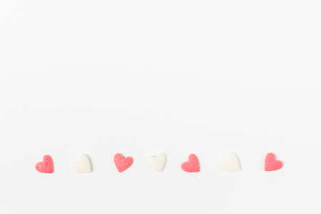Pink and white heart-shaped sugar candies on white background, minimalistic saint valentine`s day greeting cardの写真素材