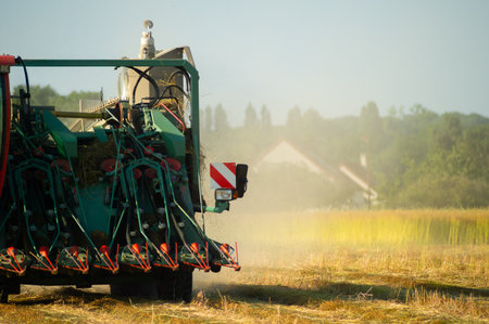 A tractor works a flax field in an active harvest process, showcasing rural power. Ideal for farming visuals, or countryside lifestyle content with a productive appeal captured.の写真素材