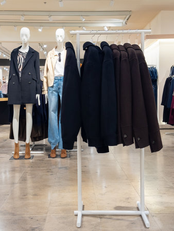 Mass market store display featuring trendy autumn and winter outerwear, including coats on mannequins and hangers. Showcases seasonal fashion and retail interior.の写真素材