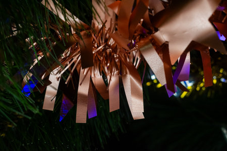 Detailed shot of copper streamer decorations and stars interwoven with colorful LED string lights and a power cable on a New Years holiday tree. Reflects festive atmosphere and celebration.の写真素材