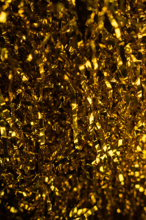 A vibrant, vertical macro shot of shimmering gold streamers and tinsel with bokeh lights, creating a rich texture. Symbolizes luxury, celebration, and the excitement of New Years Eve.の写真素材