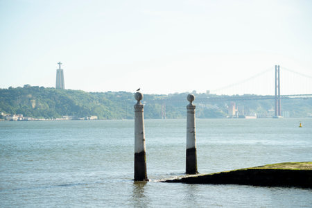 Cais das Colunas pillars standing majestically in the Tagus River, with the city's iconic landmarks in the background.の写真素材