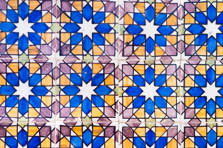 A detailed view of a repeating Azulejo tile pattern on a wall in Pena Palace, Sintra. The geometric design features stars in blue, yellow, and purple colors.の写真素材