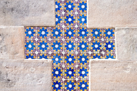 A cross-shaped decorative motif made of Azulejo tiles is set into an old, rough stone wall at Pena Palace, Sintra. The pattern is blue, yellow, and white.の写真素材
