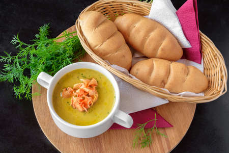 Soup-puree in a white plate on a black background with bread