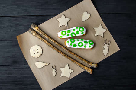 Eclairs with white glaze on a craft sheet on a black wooden background taken from above