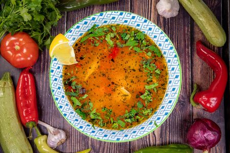 Tasty fish soup with spices and lemon, on a wooden table. Top viewの写真素材