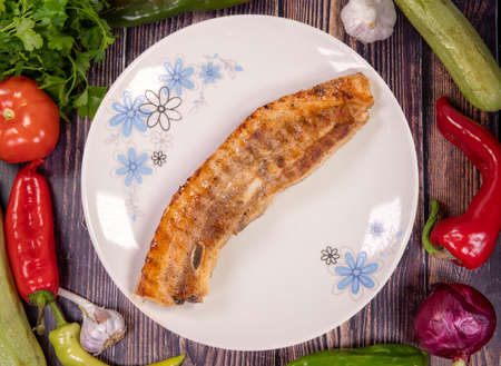 Tasty grilled pork belly in a plate on a wooden table, top viewの写真素材