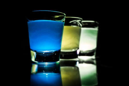 Three glasses filled with coloured waterの写真素材