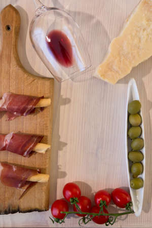 Red wine with cheese, olives, tomatoes, prosciutto on a white wooden backgroundの写真素材