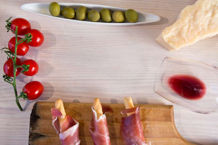 Red wine with cheese, olives, tomatoes, prosciutto on a white wooden backgroundの写真素材