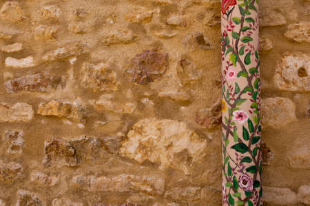 ocher plaster stonewall with a pipe decorated with a floral pattern in Provence, Franceの写真素材