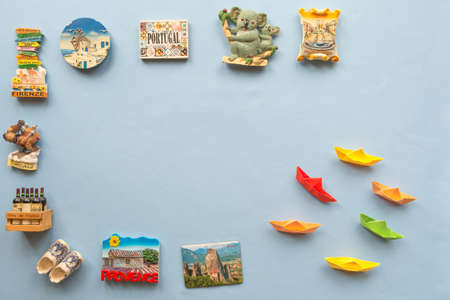 colorful paper ships and  various souvenir magnets from several world country arranged on the blue backgroundの写真素材
