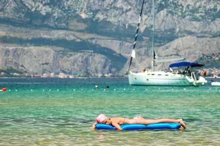 Gorgeous scenic view of young girl sunbathing on Adriatic waters in Croatiaの写真素材