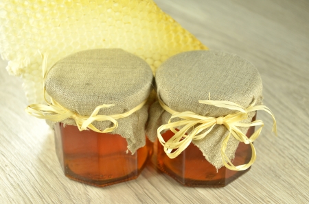 two jars of fresh delicious honey with honeycombの写真素材
