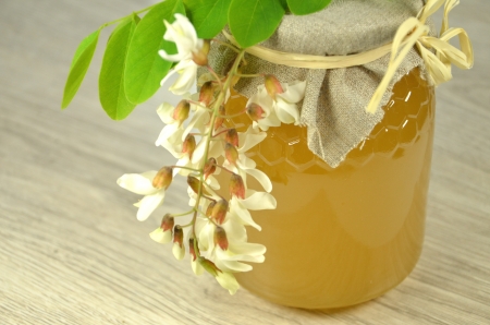jar of fresh delicious honey with acacia flowers and honeycombの写真素材