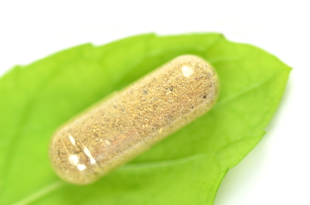 closeup of herbal capsule on mint leaf isolated on white の写真素材