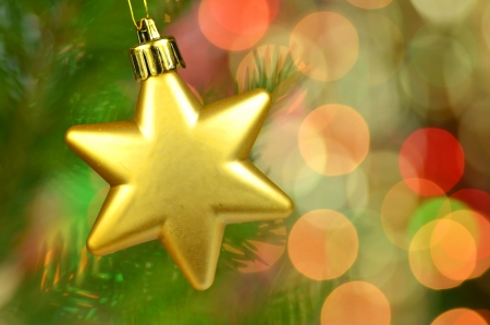 christmas decoration, golden Christmas star ball hanging on spruce twig against bokeh backgroundの写真素材