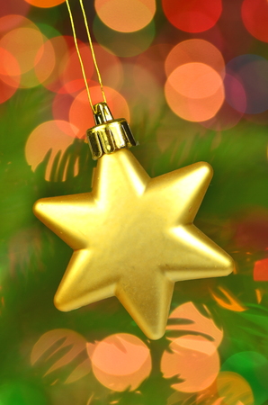 christmas decoration, golden Christmas star ball hanging on spruce twig against bokeh backgroundの写真素材