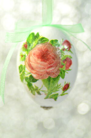 Easter egg decorated with flowers made by decoupage technique on bokeh backgroundの写真素材