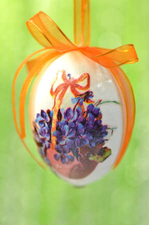 Easter egg decorated with flowers made by decoupage technique on green backgroundの写真素材