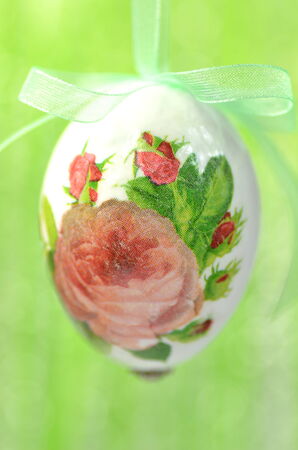 Easter egg decorated with flowers made by decoupage technique on green backgroundの写真素材