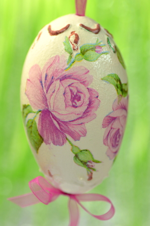 Easter egg decorated with flowers made by decoupage technique on green backgroundの写真素材