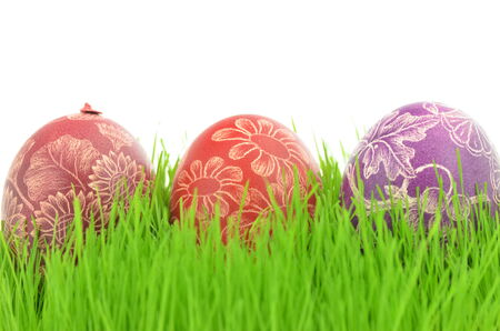 three scratched handmade Easter eggs in the grass isolated on white backgroundの写真素材