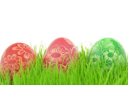 three scratched handmade Easter eggs in the grass isolated on white backgroundの写真素材