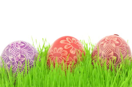 three scratched handmade Easter eggs in the grass isolated on white backgroundの写真素材