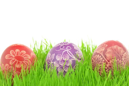 three scratched handmade Easter eggs in the grass isolated on white backgroundの写真素材