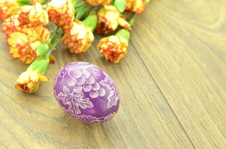 scratched handmade Easter egg and carnation flowersの写真素材