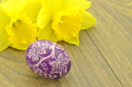scratched handmade Easter egg and daffodil flowersの写真素材