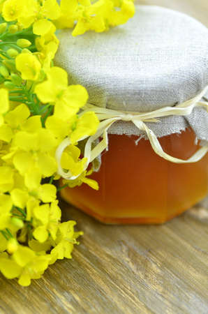 jar of delicious honey in a jar with rapeseed flowers の写真素材