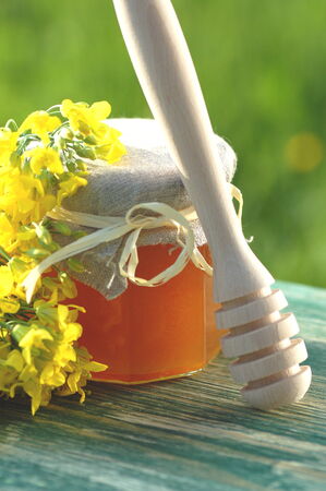 jar of delicious honey with rapeseed flowers and honey dipperの写真素材