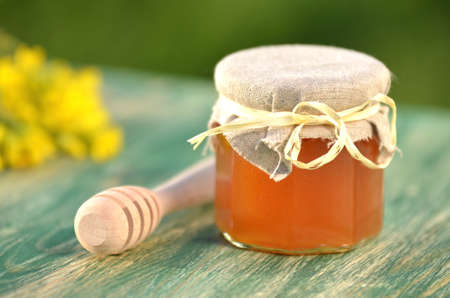 jar of delicious honey with rapeseed flowers and honey dipperの写真素材