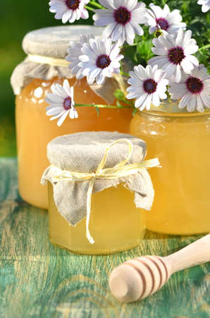 jars of delicious honey, flowers and honey dipper in apiaryの写真素材