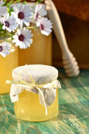 jars of delicious honey, flowers and honey dipper in apiaryの写真素材