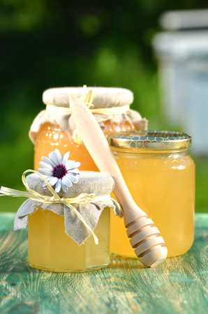 jars of delicious honey, flowers and honey dipper in apiaryの写真素材