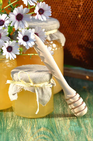 jars of delicious honey, flowers and honey dipper in apiaryの写真素材