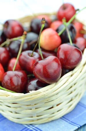 closeup of ripe, fresh and sweet cherries in wicker basketの写真素材
