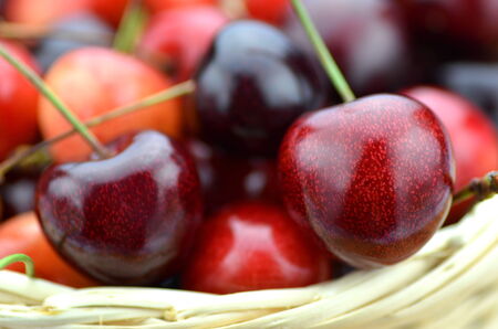 closeup of ripe, fresh and sweet cherries in wicker basketの写真素材
