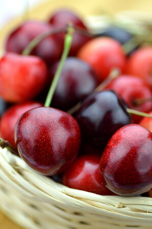 closeup of ripe, fresh and sweet cherries in wicker basketの写真素材