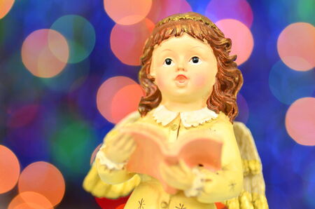 christmas decoration, figure of singing angel against bokeh backgroundの写真素材