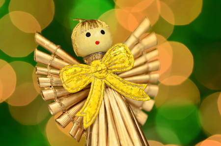 christmas decoration, golden angel made of straw against bokeh backgroundの写真素材