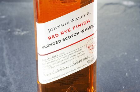 Johnnie Walker red rye finish blended whiskey on stone slate background. Johnnie Walker was established in 1820 in Kilmarnock, Scotlandのeditorial素材