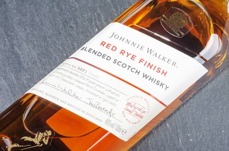 Johnnie Walker red rye finish blended whiskey on stone slate background. Johnnie Walker was established in 1820 in Kilmarnock, Scotlandのeditorial素材
